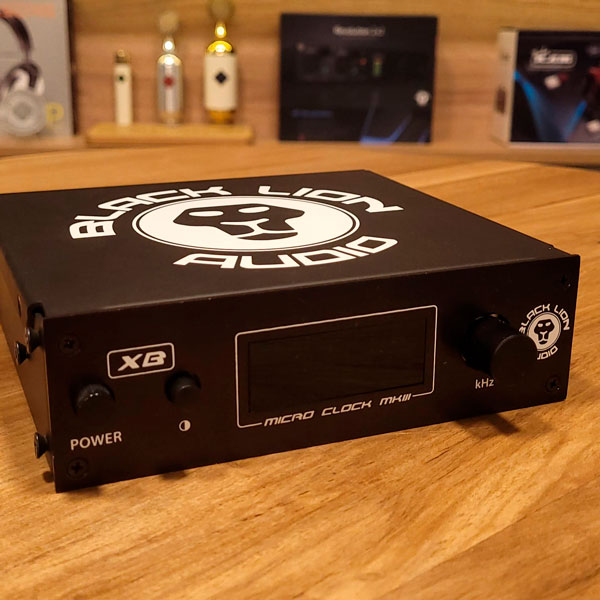Black Lion Microclock Mk3 sobre mesa de madera con equipamiento de audio de fonfo